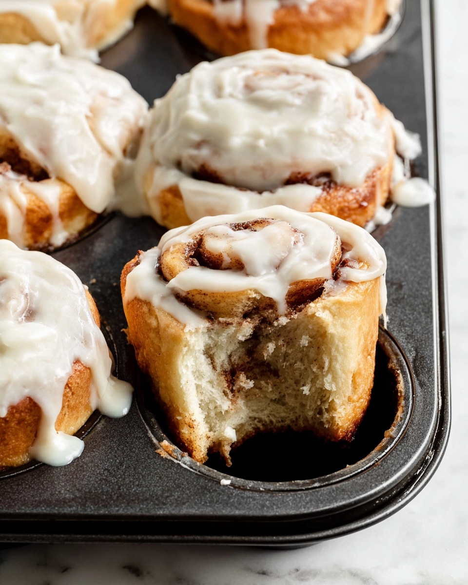The image shows two black metal muffin trays placed side by side on a white marbled surface. The left tray contains twelve unbaked cinnamon rolls with visible light dough spirals layered with dark cinnamon filling, each roll slightly risen but still soft and pale in color. The right tray shows the same cinnamon rolls after baking, now puffed up and golden brown, with deeper caramelization on the swirl edges and a toasted dark brown cinnamon layer on top. Both trays are arranged in a 3 by 4 grid, highlighting the clear contrast between the raw dough and the baked rolls. Photo taken with an iphone --ar 4:5 --v 7