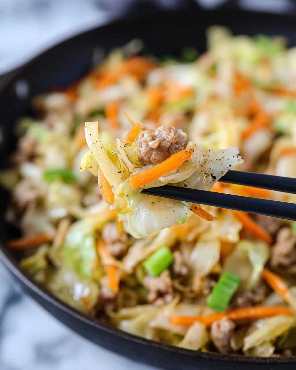A large silver pan filled with a cooked mix of light green cabbage pieces, small brown bits of meat, and thin orange carrot shreds, all mixed together with small green onion slices sprinkled on top. The food looks soft with a slight shine. A woman's hand holds a spatula with a wooden handle inside the pan, lifting some of the mixture. The pan sits on a dark blue cloth over a white marbled surface, with whole orange carrots, green onions, and loose cabbage pieces scattered around. Photo taken with an iphone --ar 4:5 --v 7