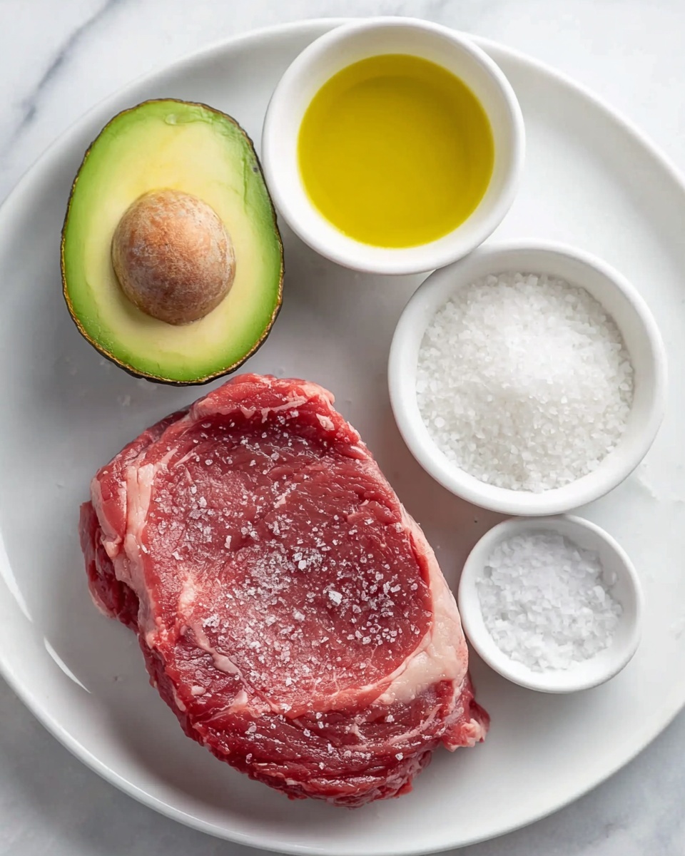 The image shows a white plate on a white marbled surface with four food items arranged on it. There is one large raw red steak with visible marbling and bits of white fat around the edges, lightly sprinkled with salt, positioned on the right side of the plate. On the upper left corner of the plate, there is a halved avocado showing its green flesh and large brown seed. Next to the avocado on the right, a small white bowl filled with yellow olive oil sits. Below the avocado, there is a larger white bowl filled with coarse white sea salt, and below it, a smaller white bowl contains more coarse salt. The setup is clean and bright, highlighting fresh ingredients photo taken with an iphone --ar 4:5 --v 7