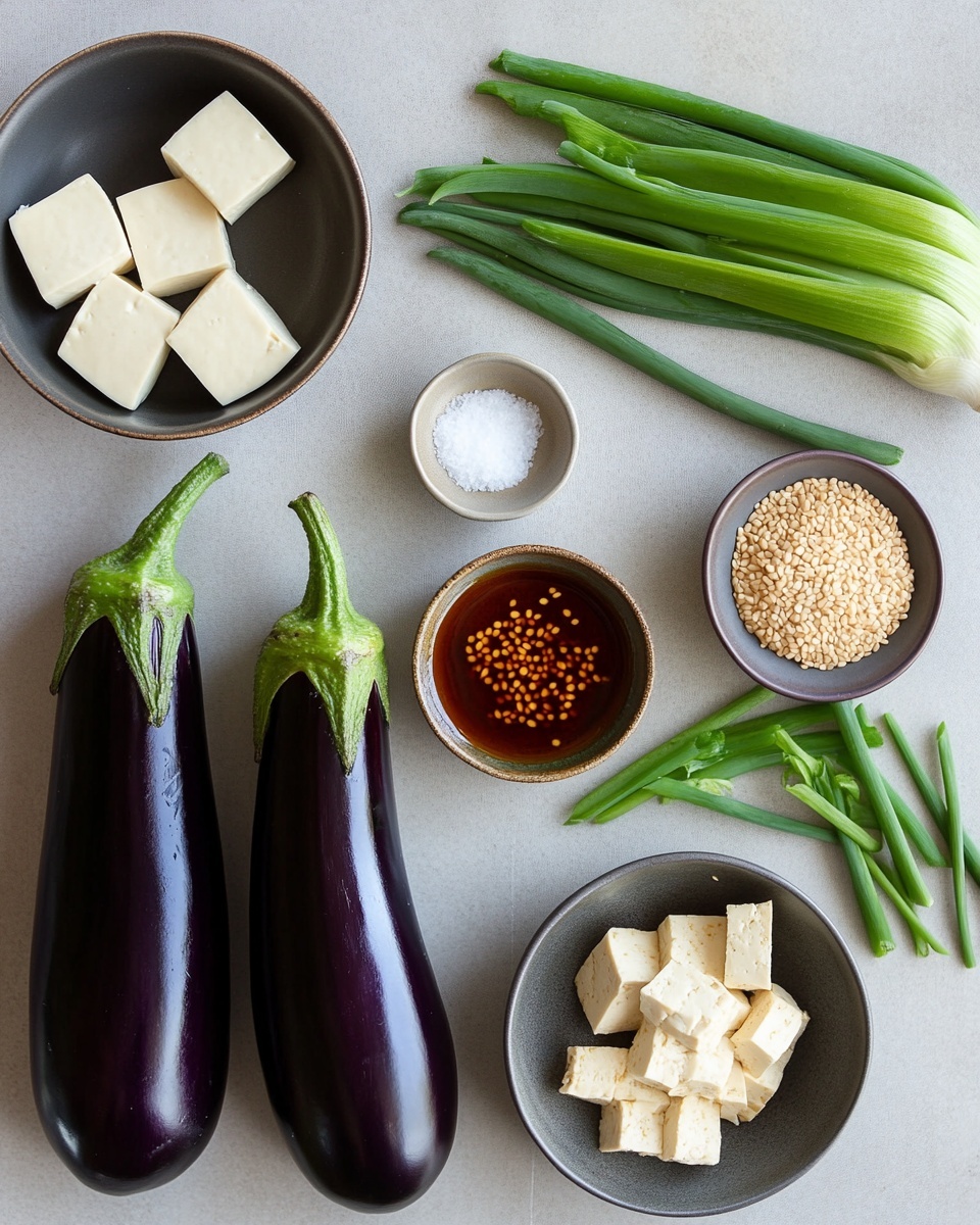 The image shows a gray frying pan filled with a cooked dish on a black stove. The dish has several light beige tofu cubes spread unevenly in a thick orange-brown sauce. There are dark purple eggplant pieces, some long and whole, mixed throughout the sauce. Small green vegetable bits are scattered on top, and there are visible droplets of oil and seasonings adding texture to the sauce’s surface. The pan’s handle extends out of the frame on the right side. The background is softly blurred with a white marbled texture underneath the stove. Photo taken with an iphone --ar 4:5 --v 7